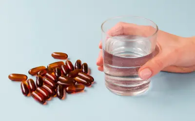Kapsułki i szklanka wody. Suplementy z **jodem na co pomagają**? Wspierają tarczycę i metabolizm.