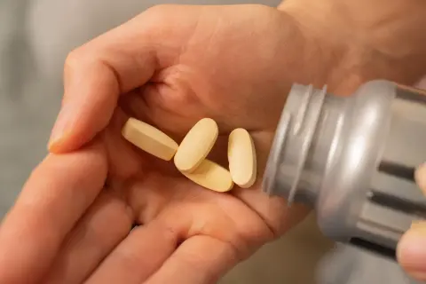 Dłoń z kilkoma tabletkami, które mogą pomóc w leczeniu dny moczanowej, gdy stosuje się witaminę B12.