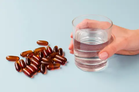 Kapsułki i szklanka wody. Suplementy z **jodem na co pomagają**? Wspierają tarczycę i metabolizm.