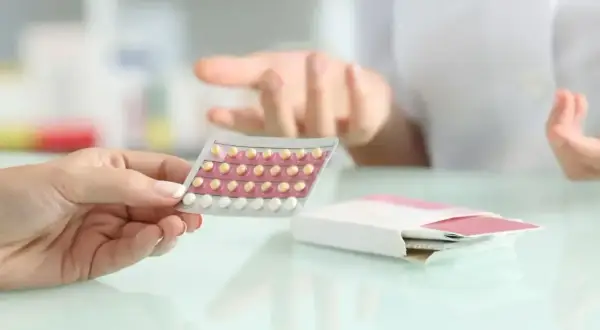 Dłoń trzyma blister tabletek antykoncepcyjnych. Farmaceuta wyjaśnia, bibloc na co.