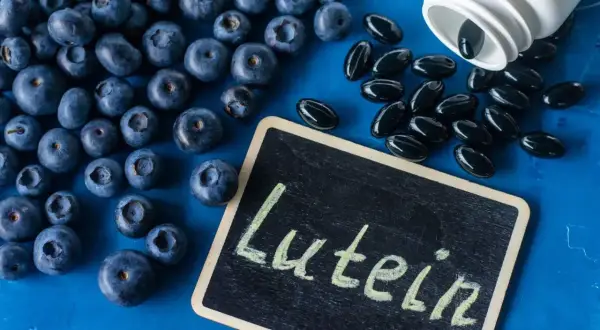 Jagody i kapsułki suplementu diety z napisem "Luteina" na tabliczce. Luteina na oczy wspiera zdrowie wzroku.
