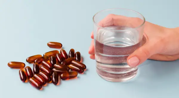 Kapsułki i szklanka wody. Suplementy z **jodem na co pomagają**? Wspierają tarczycę i metabolizm.