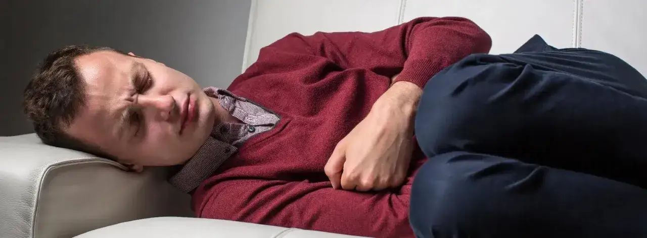 osoba z bólem brzucha i zmęczeniem