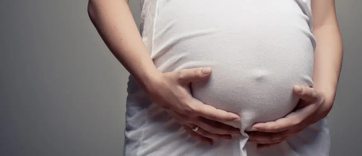 kobieta dotyka brzucha z zamyśleniem, wczesna ciąża